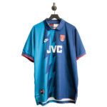 Blue and teal soccer jersey with JVC sponsor, Nike logo, and team crest, hanging on a hanger against a white background.