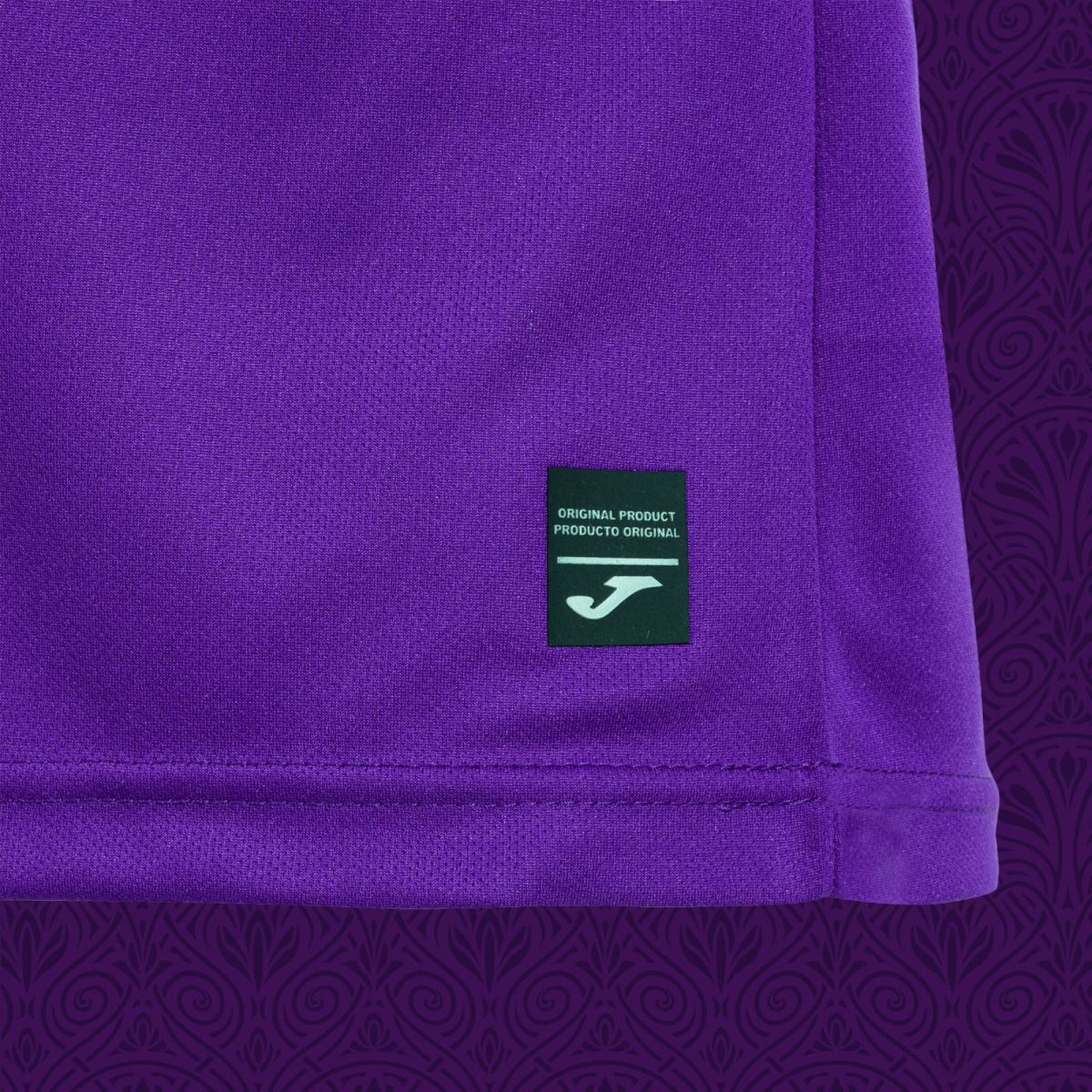 Close-up of purple fabric with a small dark green tag reading 'ORIGINAL PRODUCT / PRODUCTO ORIGINAL' and a white logo below.