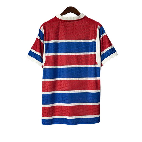 Red, white, and blue horizontal striped rugby shirt hanging on a wooden hanger from the back view.