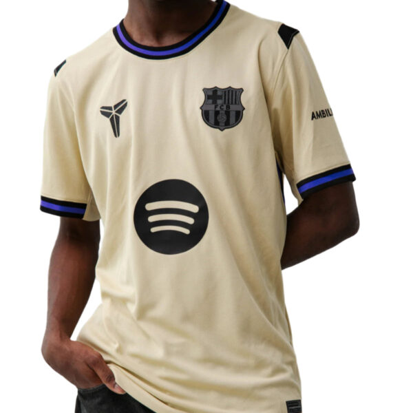 Beige soccer jersey with blue trim, crest on left chest, and a large Spotify logo on the front.
