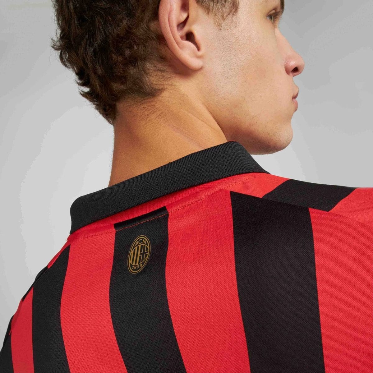 Side view of a person wearing a red and black AC Milan jersey, focusing on neck and collar.