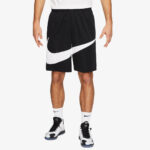 Man wearing black basketball shorts with a large white Nike swoosh design, paired with a white shirt and sneakers.