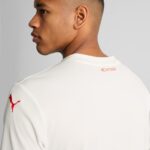 Side profile of a man wearing a white shirt with a red Puma logo on the sleeve.