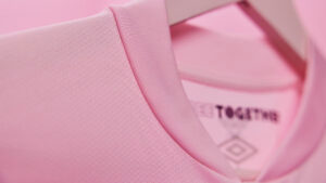 Close-up of a pink sneaker fabric with a 'TOGETHER' tag and Umbro diamond logo.