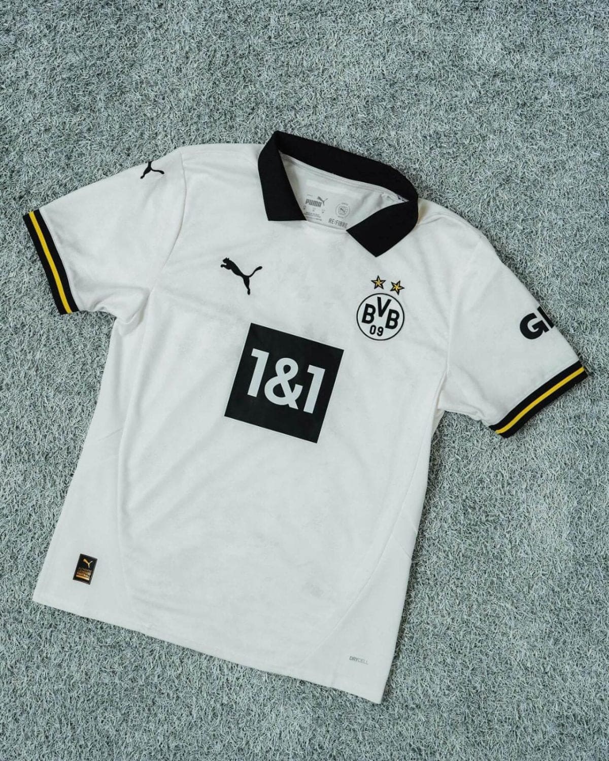 White Borussia Dortmund football jersey with black collar, featuring the BVB badge with two stars and sponsor '1&1' on the front.