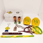 Neymar Jr. memorabilia laid out: yellow number-10 armbands, two figurines, keychain, dog tag, bracelets, and a Brazil crest tin box.