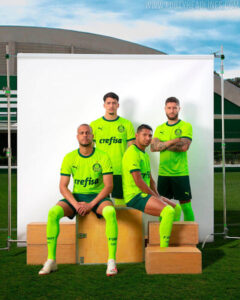 Four soccer players in neon green jerseys pose for a team photo in front of a white backdrop outdoors, with sponsor 'crefisa' visible on their shirts.