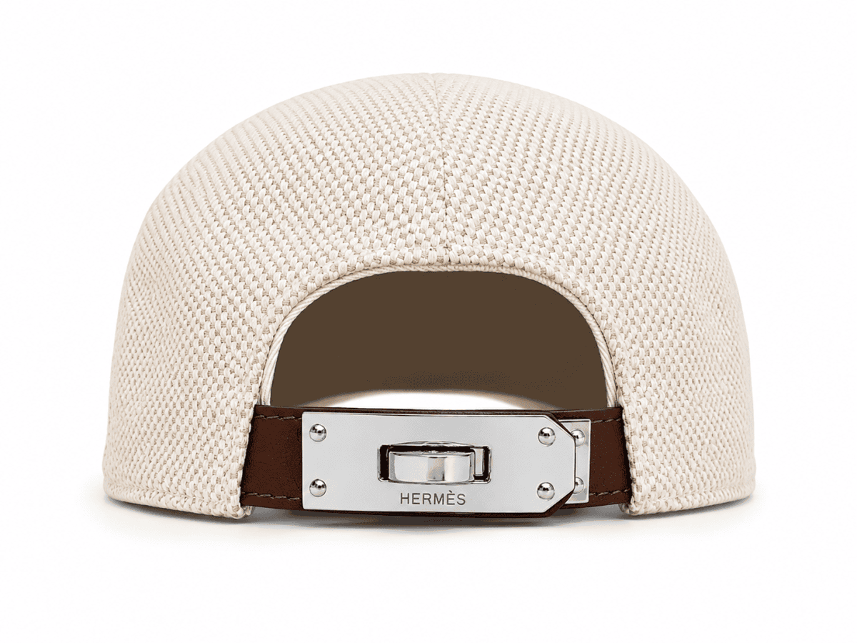 Back view of a beige woven cap with a brown leather strap and silver clasp labeled HERMÈS.