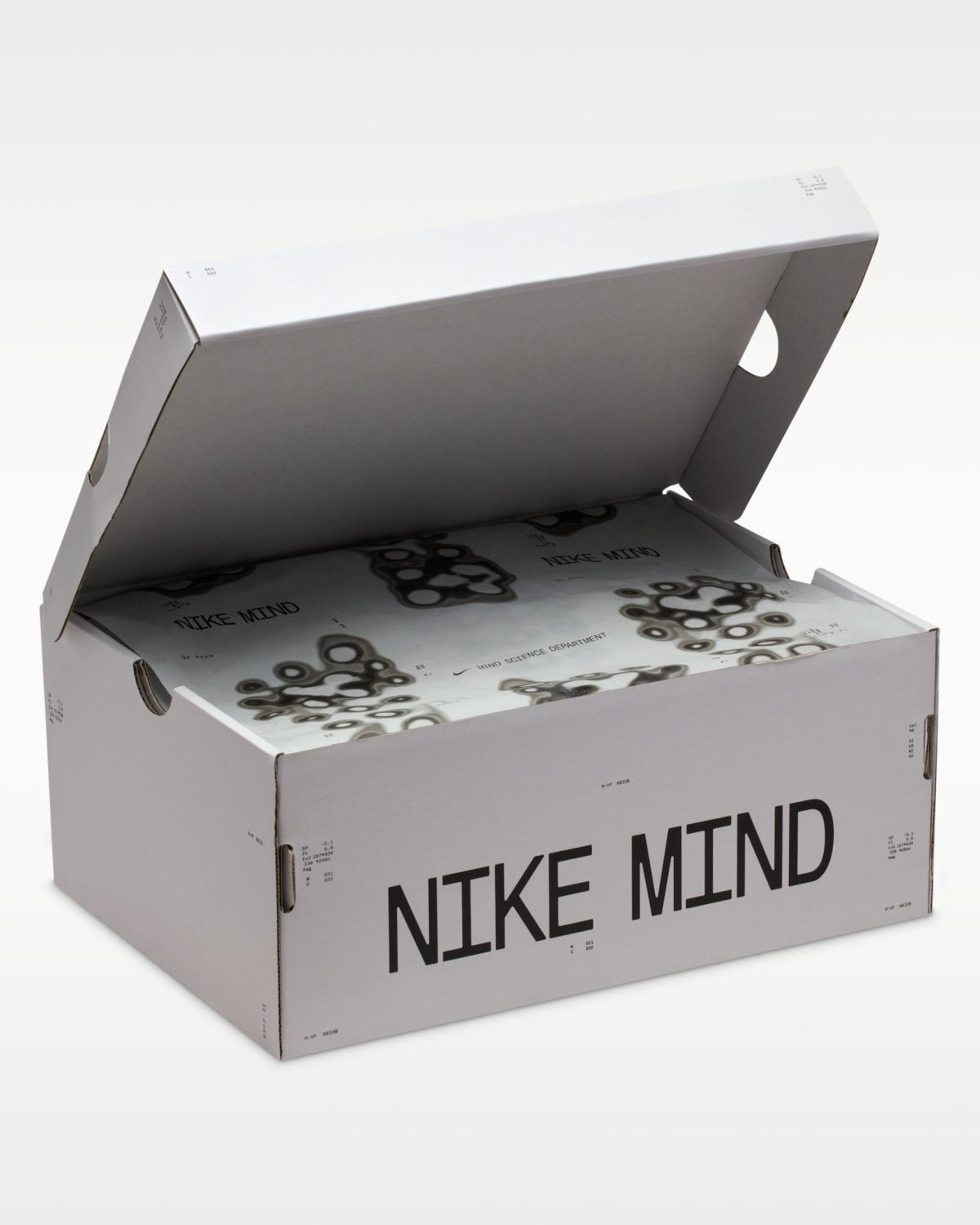 Open white Nike Mind shoebox with lid raised, showing inner packaging and repeating 'NIKE MIND' text across an illustrated pattern.