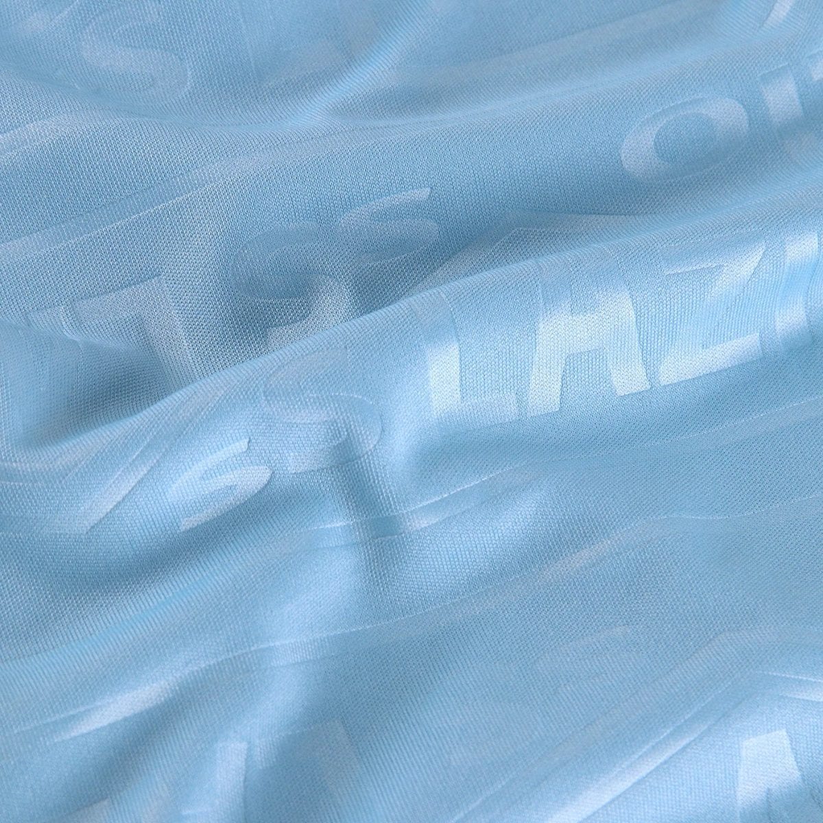 Close-up of light blue textured fabric with soft folds and a smooth weave.