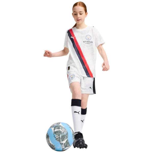 Young girl in a white soccer kit dribbles a blue and white ball on a white background.