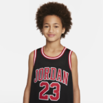 Young person with curly hair wearing a black Jordan basketball jersey with the number 23, smiling at the camera.
