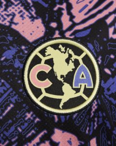 Close-up of a circular embroidered patch showing a beige world map and the letters CAP on dark fabric with pink and blue abstract patterns.