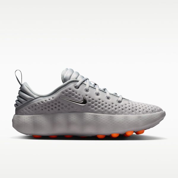 Close-up of a gray athletic sneaker showing the dotted upper, laces, and orange-tipped studs on the sole with a metallic swoosh.
