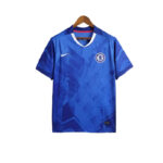 Camiseta-Chelsea-FC-1_-Equipacion-2526camisetafutboles-800x800-1 | UAE SPORT STORE Blue Chelsea FC football jersey on a hanger with white V-neck trim and Nike swoosh on the chest.