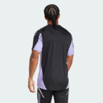 Back view of a man wearing a black athletic jersey with lavender side panels over a lavender shirt and black shorts.