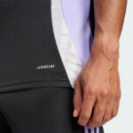 Close-up of a person's hand by black athletic shorts with a white 'AEROREADY' logo and a purple panel on the jersey.
