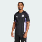 Man modeling a black Adidas soccer jersey with white stripes on the shoulders and purple side panels against a light background.