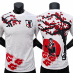 White Japan soccer jersey with bold red cherry blossom and cloud patterns, front crest visible on chest.