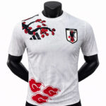 White Japan national football team jersey with Adidas logo and JFA crest, featuring a red cherry blossom graphic on the chestt.