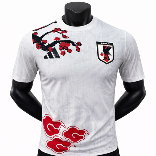 White Japan national football team jersey with Adidas logo and JFA crest, featuring a red cherry blossom graphic on the chestt.