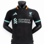 Black Liverpool FC football shirt on a mannequin with light blue Standard Chartered sponsor logo and turquoise sleeve cuffs.
