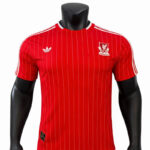 Red pinstripe football jersey with Adidas logo and club crest on the chest, displayed on a mannequin.