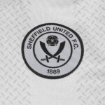 Circular Sheffield United Football Club logo on a textured background, featuring crossed swords and a rose with 1889 text.