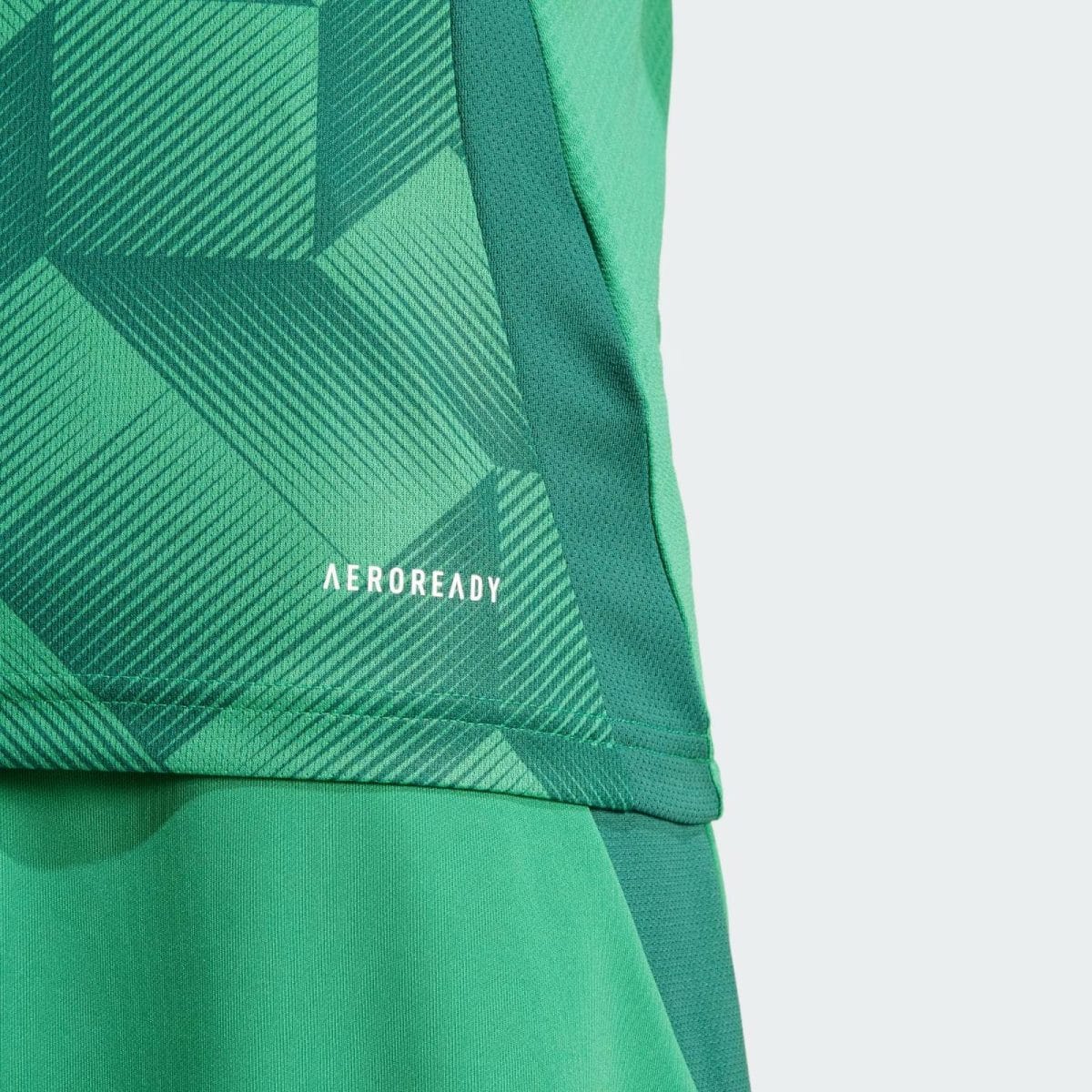 Close-up of green athletic fabric with a diagonal geometric pattern and the brand name AEROREADY visible at the bottom left.