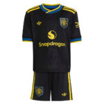 Manchester United football kit in black with yellow trim and Snapdragon sponsor on the jersey, plus matching black shorts with yellow stripes and crest.