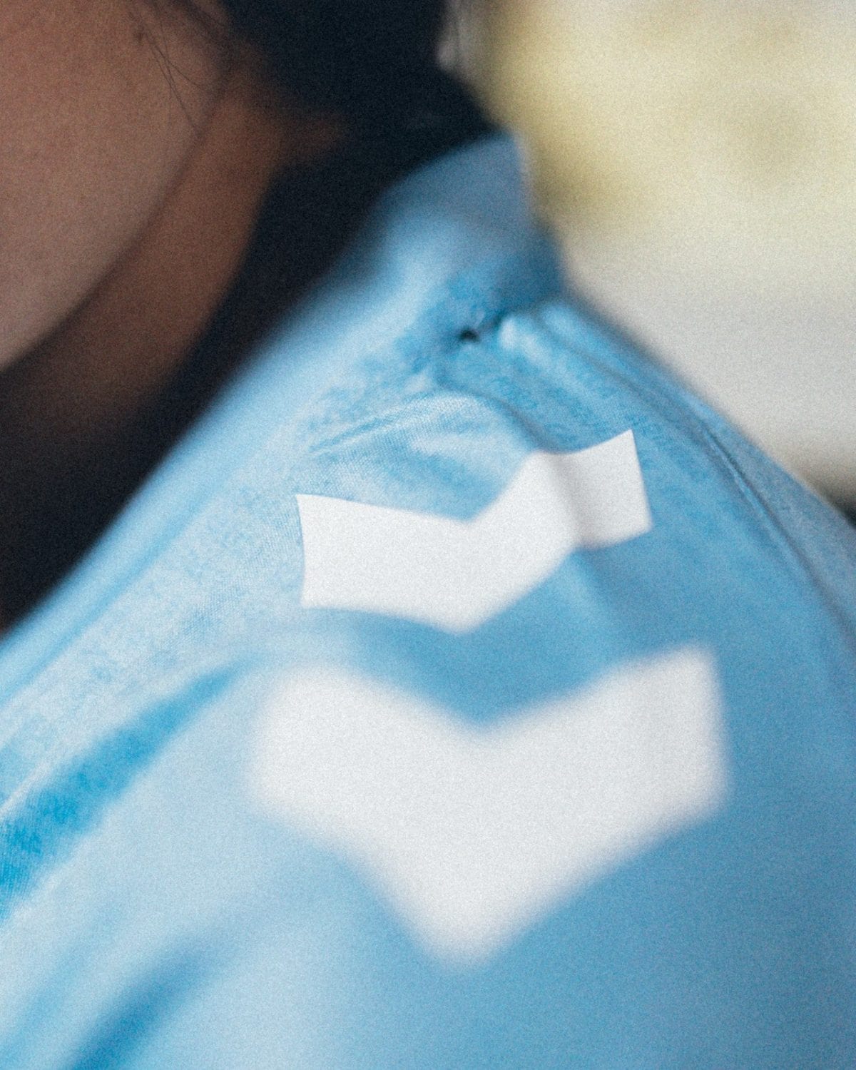 Close-up of a light blue fabric with white rectangular patches or tape-like shapes.