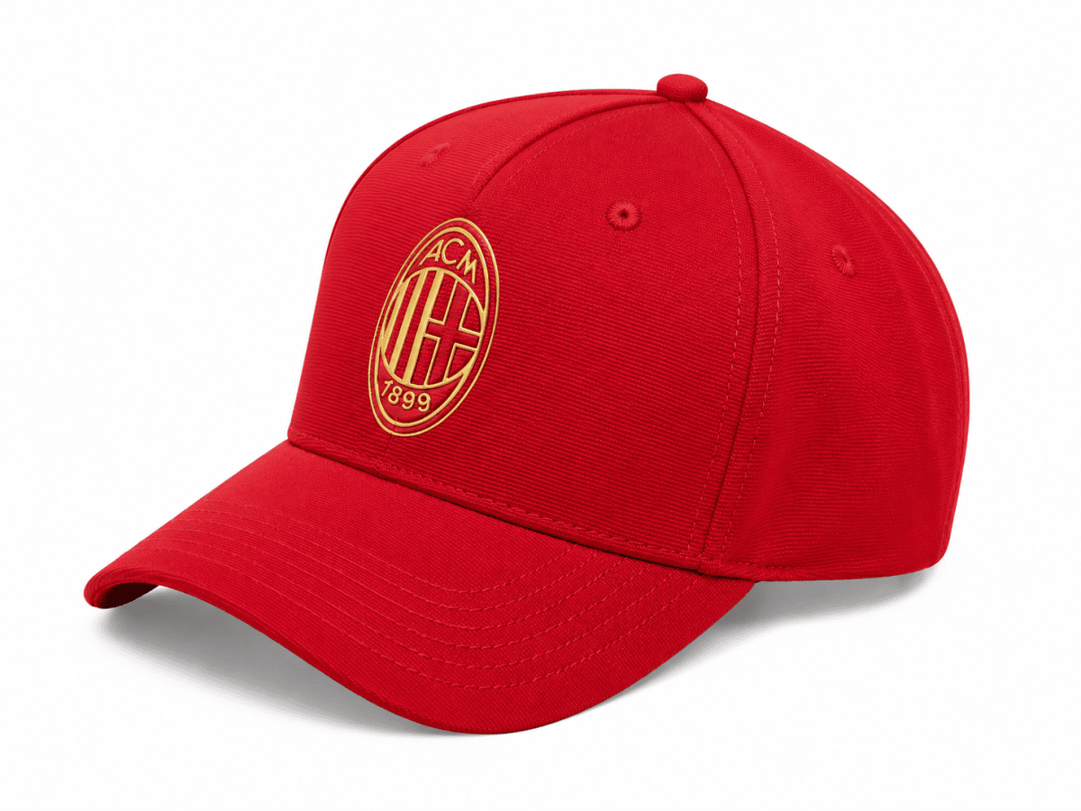 Red baseball cap with a curved brim and a gold AC Milan emblem on the front panel.