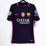 DSC2439 | UAE SPORT STORE Dark blue FC Barcelona soccer jersey with pink accents on a hanger, featuring Qatar Airways sponsor text, Nike swoosh, Barca crest, and UEFA/Champions League patches on the sleeves.