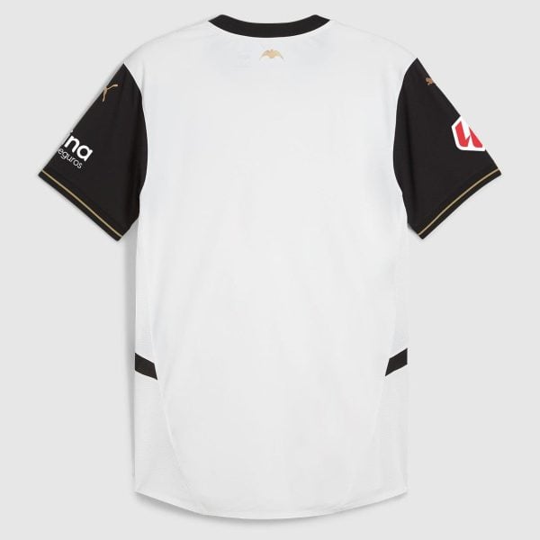 Back view of a white athletic jersey with black sleeves and gold trim accents on the cuffs and shoulders photographed against a gray background.