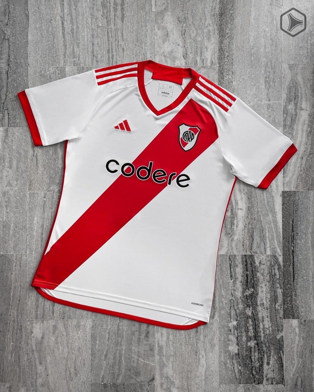 White River Plate football jersey laid flat with a red diagonal sash, red trim, and sponsor logo Codere on a gray tiled floor.