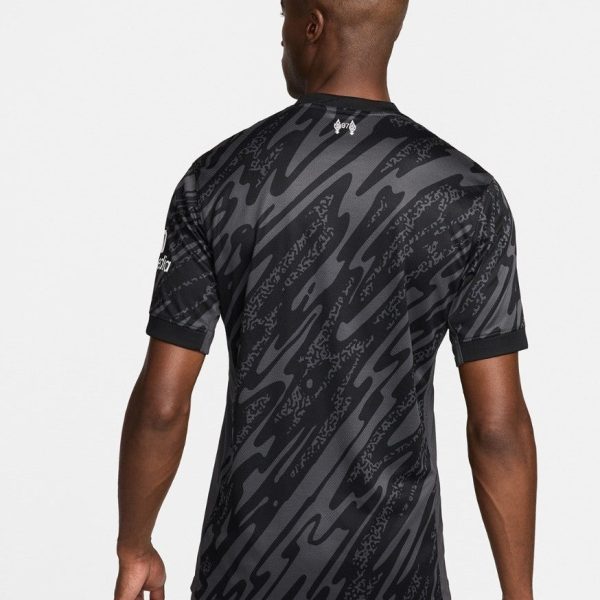 Man wearing a black and gray patterned athletic jersey, shown from the back, with rolled cuffs and a small logo near the neckline