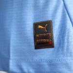 Close-up of blue fabric with a black badge reading 'AUTHENTIC LICENSED FOOTBALL' and a Puma logo above it.