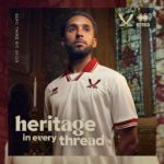 Portrait of a man in a cream Errea sports jersey inside a church-like setting, with the slogan 'heritage in every thread' and brand logos visible.