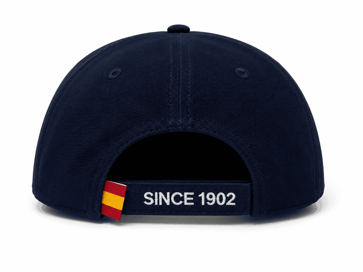 Navy baseball cap shown from the back, with an adjustable strap reading 'SINCE 1902' and a small red-yellow tab on the left side