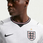 Close-up of a man in a white England football jersey with crest, star above, and Nike logo visible on the chest.