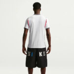 Back view of a man in a white short-sleeve shirt and black knee-length shorts with large NIKE lettering on the back of the shorts.