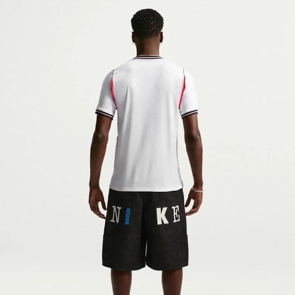 Back view of a man in a white short-sleeve shirt and black knee-length shorts with large NIKE lettering on the back of the shorts.