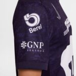 Close-up of a dark purple sports jersey sleeve showing sponsor logos, including 'Borel' circular emblem and 'GNP Seguros' text with a partial Nike swoosh nearby.