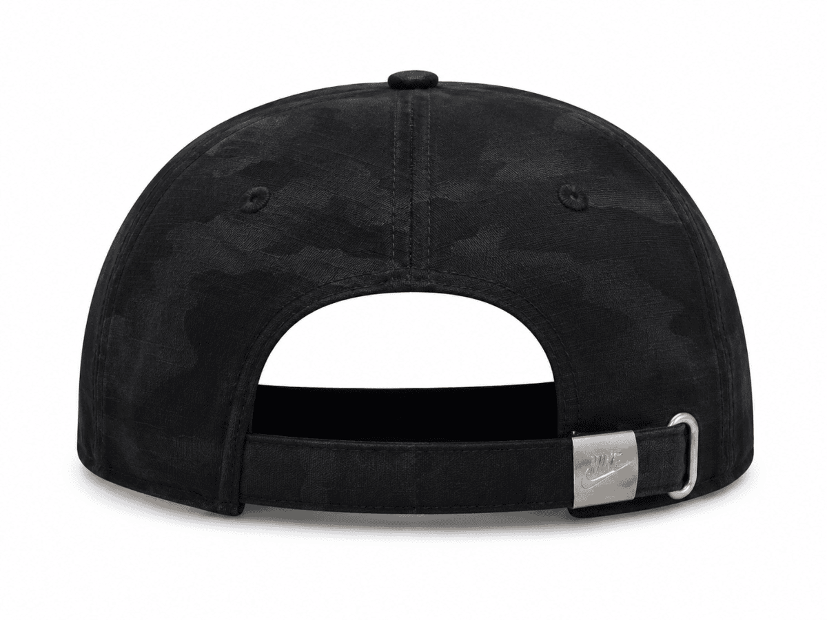 Rear view of a black camo baseball cap with an adjustable strap and metal buckle showing the Nike logo.