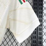 Close-up of a light beige striped polo sleeve draped over a black metal rack with a diamond-pattern chain-link fence in the background.