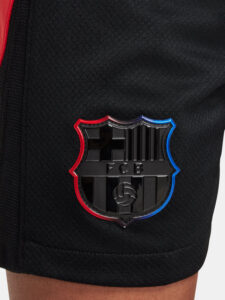Close-up of a black athletic garment featuring an FC Barcelona shield emblem outlined in red and blue.