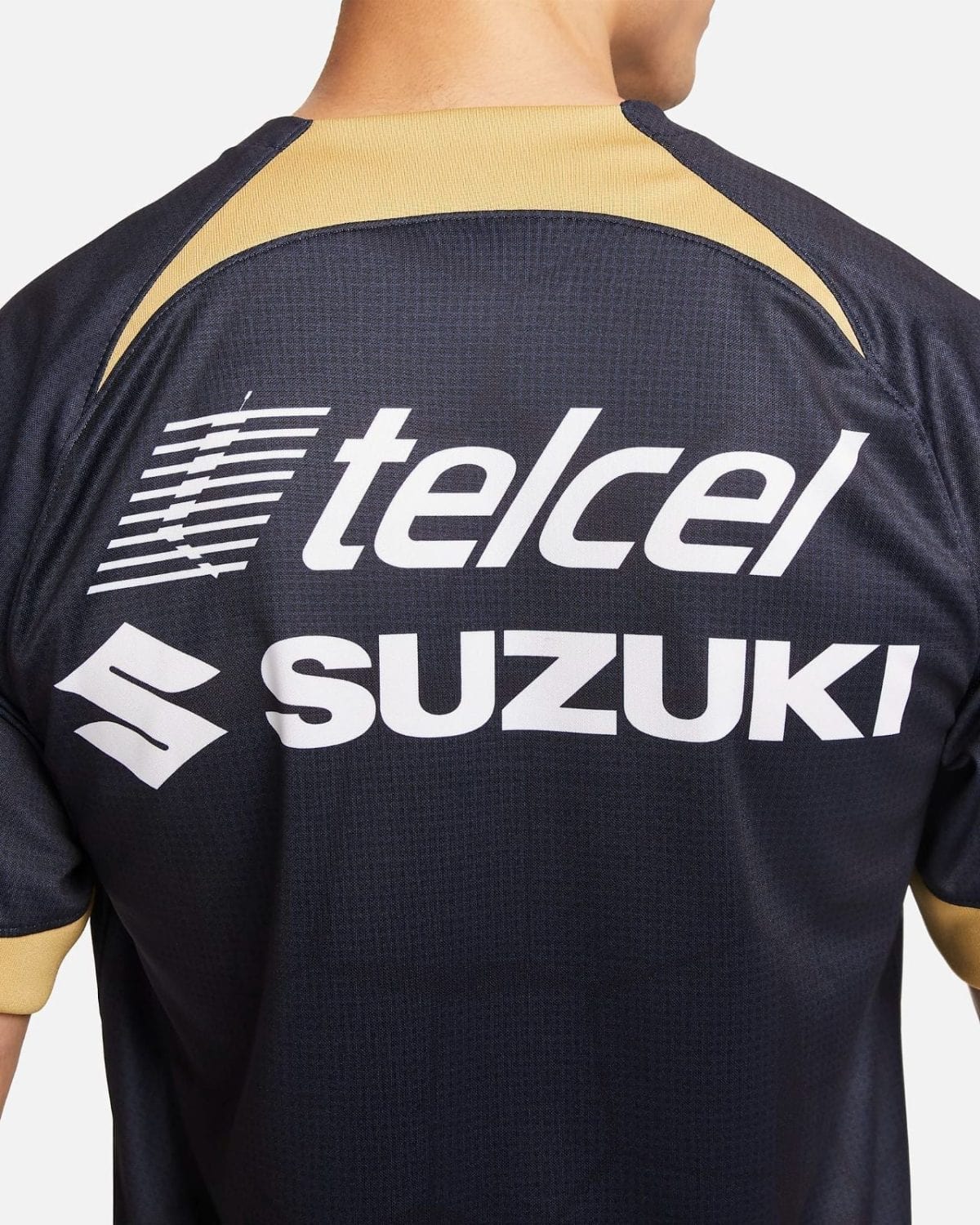 Back of a navy sports jersey with large white 'Telcel' and 'Suzuki' logos and beige/gold neck trim.