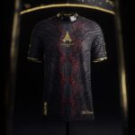 Dark patterned sports jersey on a mannequin with a gold Eiffel Tower crest and gold-trimmed sleeves.