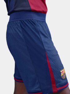 Side view of blue FC Barcelona shorts with a red stripe down the leg and the club crest near the hem on light fabric mix