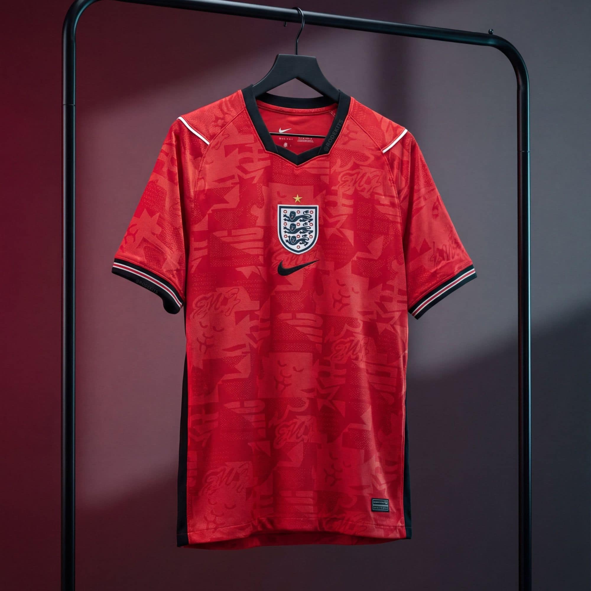 G_7O7tWXkAAjqpJ | UAE SPORT STORE Red England football jersey hanging on a black hanger against a dark red gradient backdrop, showing the crest and sponsor logos.